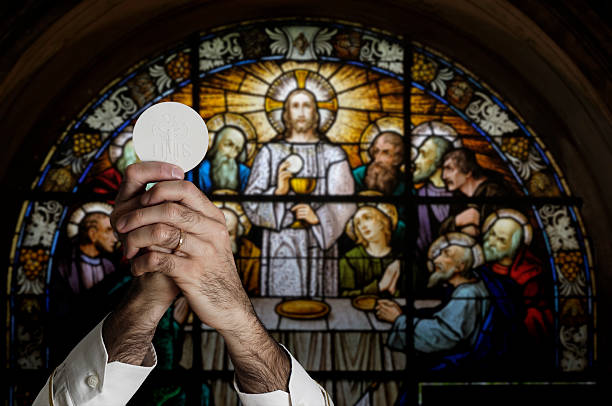 Close up of pastor giving first communion bread on woman hands in dark background