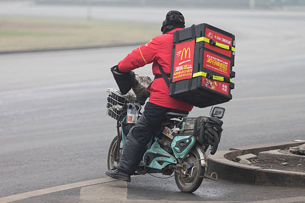 Beijing, China - December 8, 2015:  A gentleman wearing helmet is delivering McDonald food by using an E-bike in Beijing Chaoyang district.. McDonald adjusted their business model in order to success in China market.