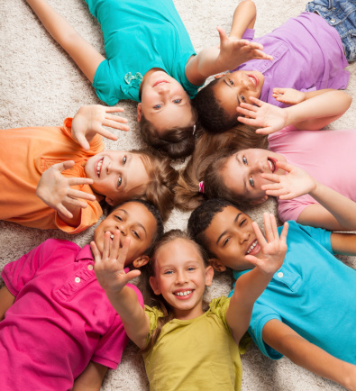 Group of happy diversity looking kids laying in star shape on the floor with lifted kids