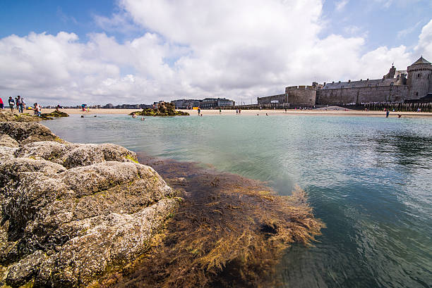 Saint Malo, Brittany, France Saint Malo, Francia. July 10, 2014. Some children are swimming in a natural pool that is created when there is low tide. costa esmeralda stock pictures, royalty-free photos & images
