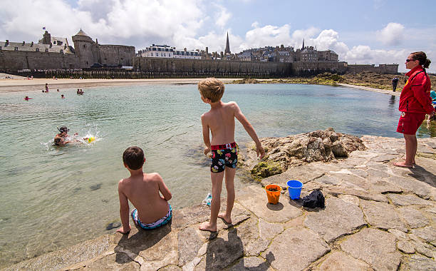Saint Malo, Brittany, France Saint Malo, Francia. July 10, 2014. Some children are swimming in a natural pool that is created when there is low tide and a lifeguard controls them. costa esmeralda stock pictures, royalty-free photos & images