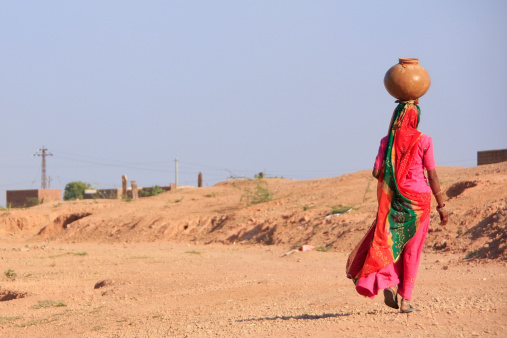Khichan, India - February 12, 2011: Local woman carrying jar with water on her head, Khichan village, Rajasthan, India.