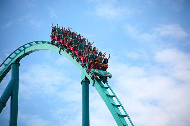 menschen auf einer achterbahn im freizeitpark - rollercoaster stock-fotos und bilder