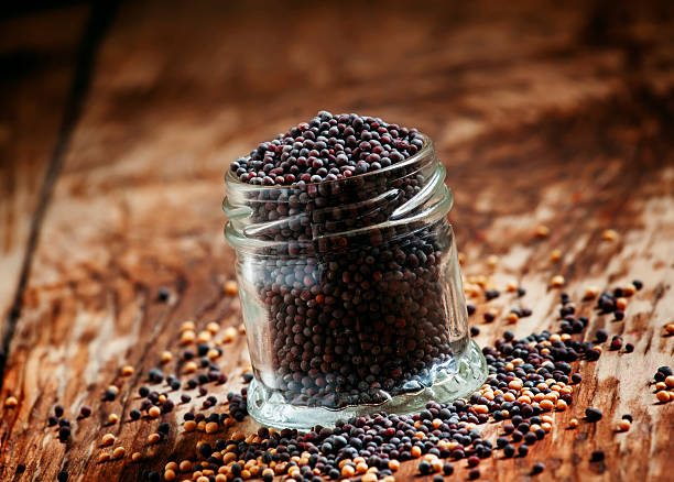 Black mustard seeds in a glass jar Black mustard seeds in a glass jar on the old wooden background, selective focus dijonnaise stock pictures, royalty-free photos & images