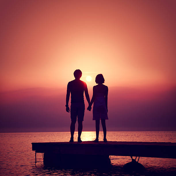 Romantic Couple Enjoying Sunset at Sea. stock photo