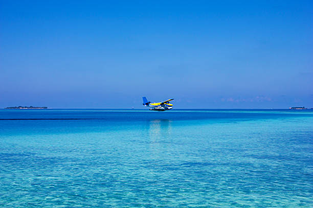 Sea plane flying on blue sky in Maldives