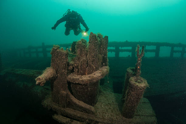 Great Lakes Shipwreck A scuba diver explores an old, wooden shipwreck in Lake Michigan. The waters of the Great Lakes are so cold that they preserve the many wrecks on bottom. great lakes stock pictures, royalty-free photos & images