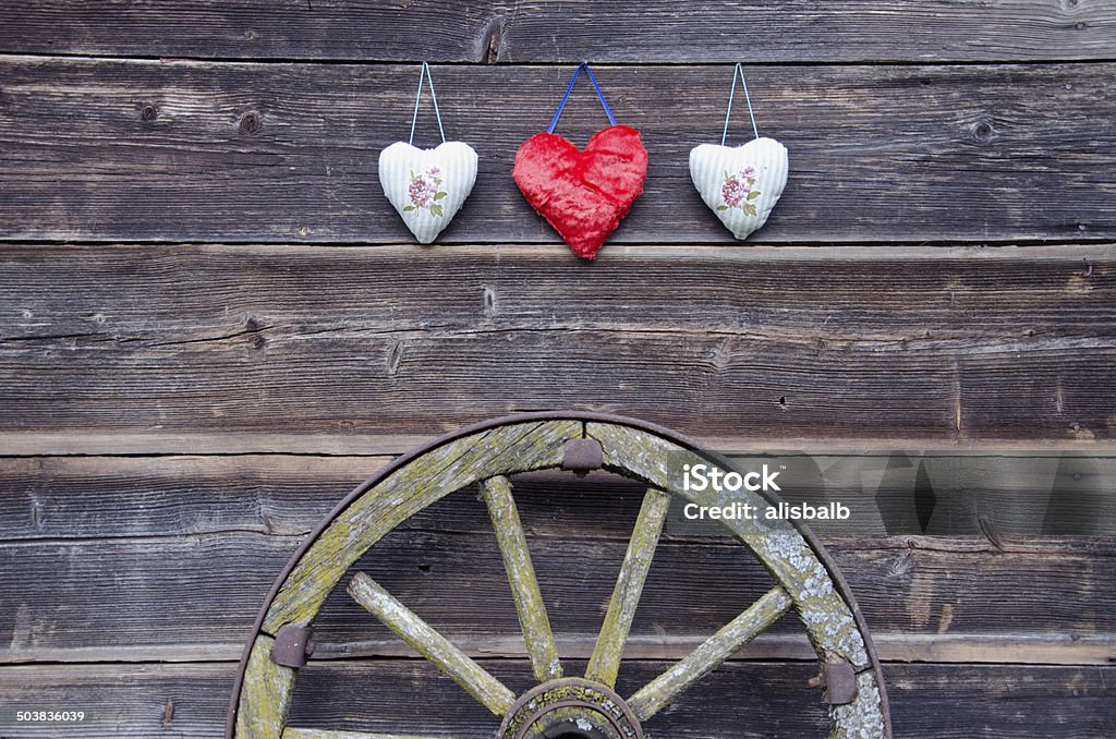 old barn wooden wall with hearts and carriage wheel old barn wooden wall with three hearts and ancient carriage wheel Barn Stock Photo