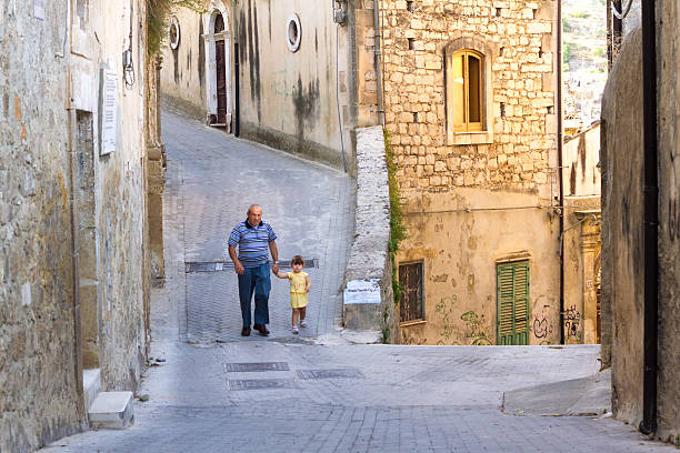 старший ходьба и держит руки с ребенком, модика, сицилия - modica photography italy sunlight стоковые фото и изображения