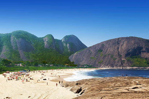 itacoatiara strand in niteroi city - tree large group of people sand sunbathing stock-fotos und bilder