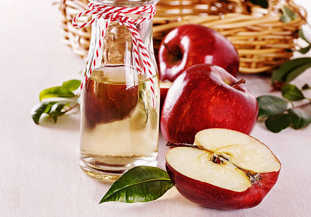 Apple cider vinegar and apples over white wooden background stock photo