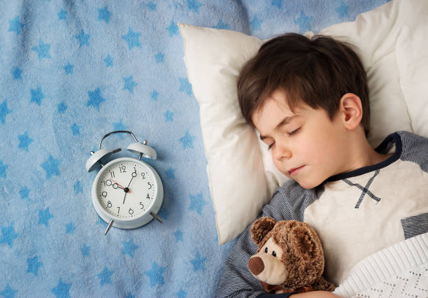 istock six years old child sleeping in bed with alarm clock 503844490