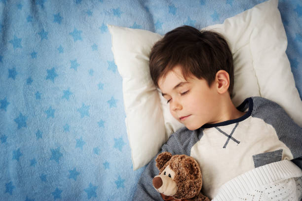 six years old child sleeping in bed with alarm clock - kussen beddengoed stockfoto's en -beelden