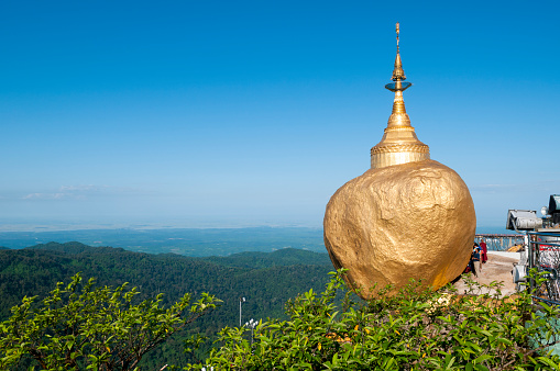 Kyaiktiyo, Burma/Myanmar - October 30, 2011: A landmark site in Myanmar and the destination of many a Buddhist pilgrim, the Golden Rock (also called the Kyaiktiyo Pagoda) is famous for how it is precariously perched on the ledge. It is said that the rock is balanced on a hair of the Buddha. People gather beside the boulder to pray, take pictures, etc.