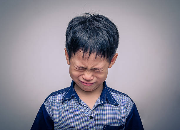 boy crying over dark background stock photo