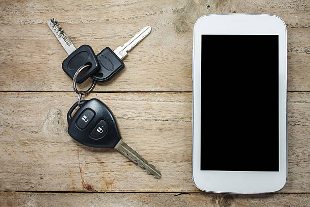 Mobile phone and car remote keys on wooden Mobile phone and car remote keys on wooden background car keys table stock pictures, royalty-free photos & images