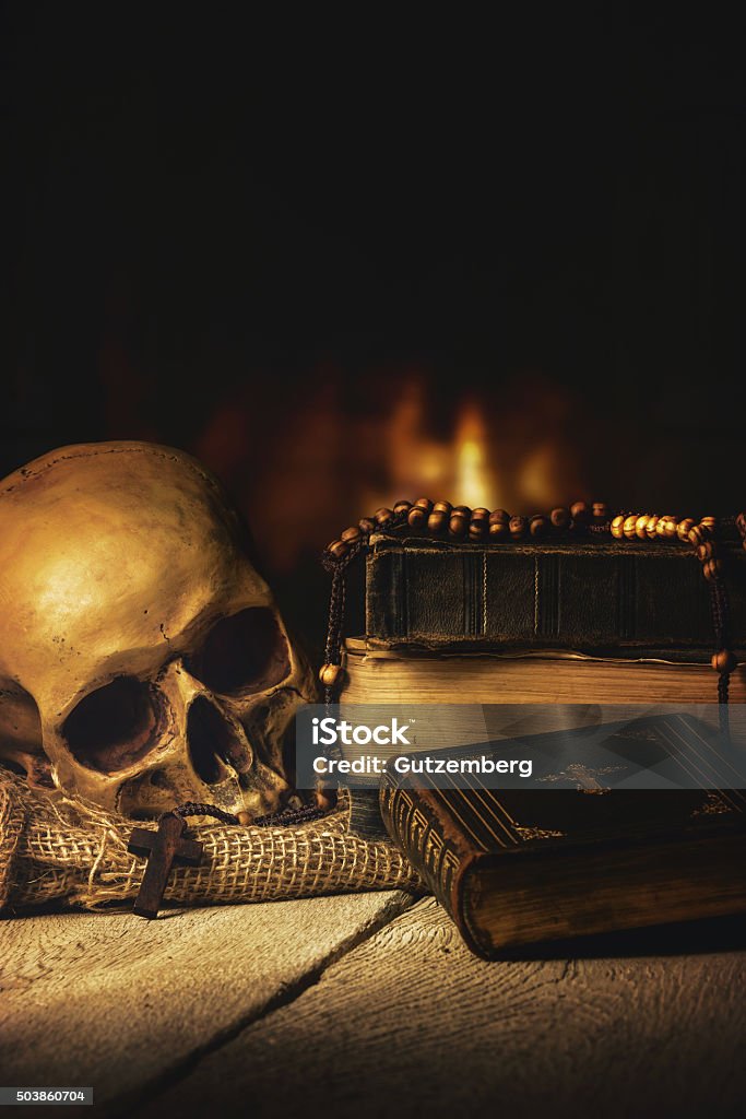 Skull with Rosary and Bible in front of a fireplace Rosary with Skull and Bible in front of a fireplace Spooky Stock Photo