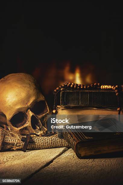 Skull With Rosary And Bible In Front Of A Fireplace Stock Photo - Download Image Now