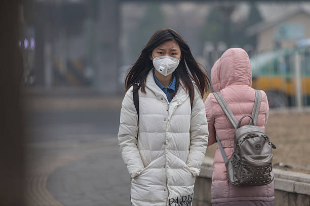 petite fille portant masque à la bouche avec filtre contre la pollution atmosphérique, beijing - beijing air pollution china smog photos et images de collection