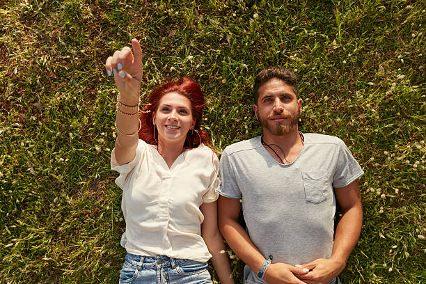 Relaxed young couple lying down on meadow