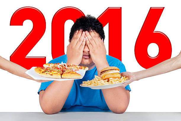 istock Overweight man with numbers 2016 refuses junk food 503868162