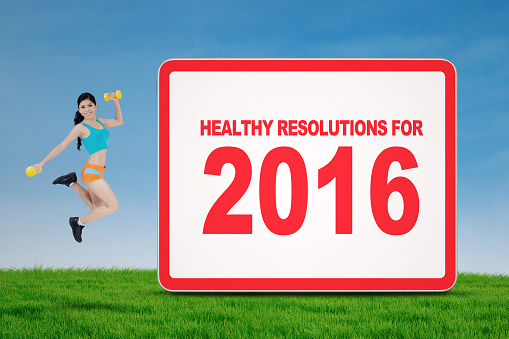 Fitness woman jumping on meadow with text of healthy resolution for 2016 at billboard
