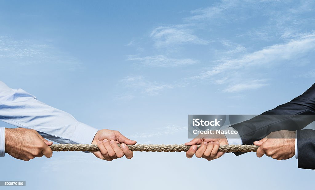 Tug of war Two businessman pulling a rope in opposite directions over sky background with copy space Competition Stock Photo