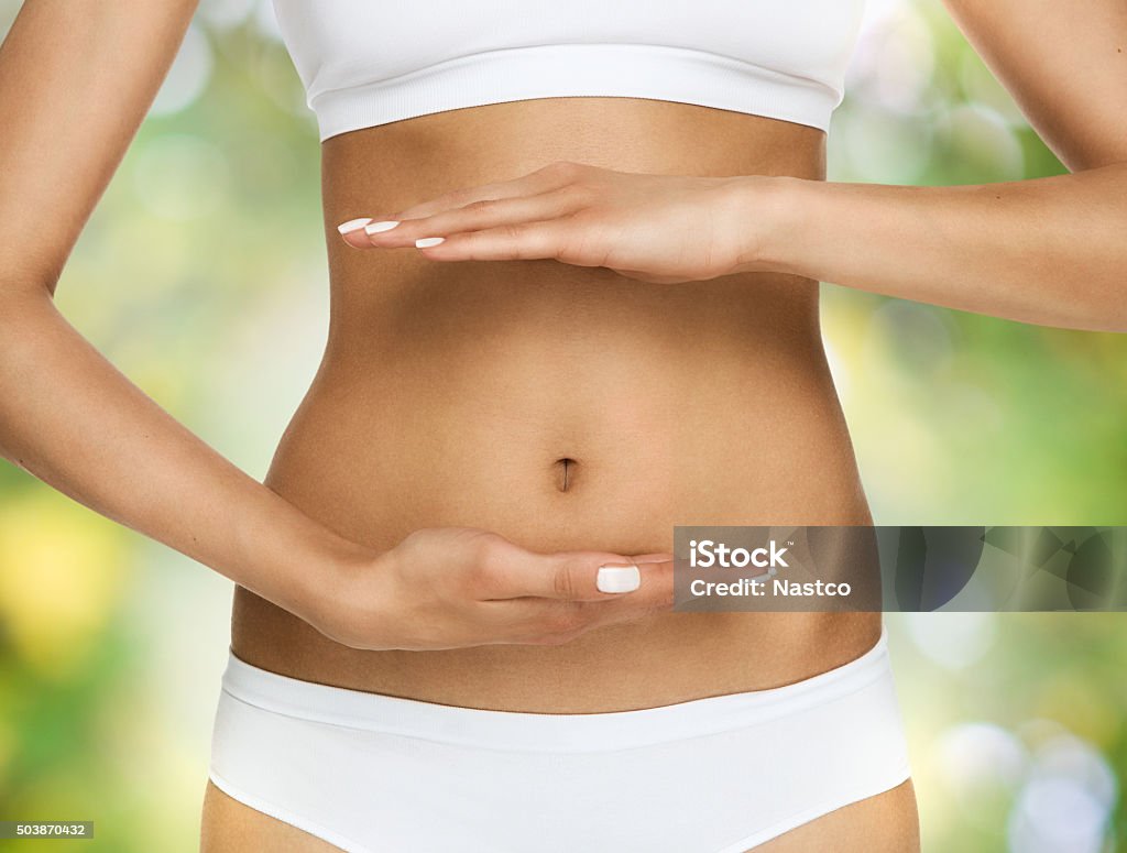 Pregnancy or diet concept Female hands protecting the stomach over green, nature background Abdomen Stock Photo