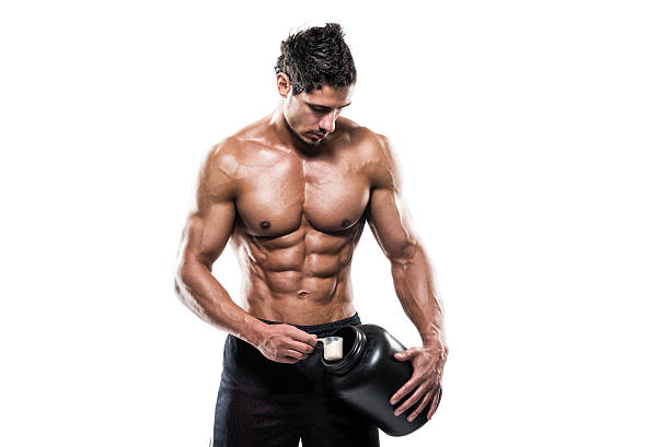 athlète masculin tenant une bouteille avec un supplément de poudre - protein protein drink ground whey photos et images de collection