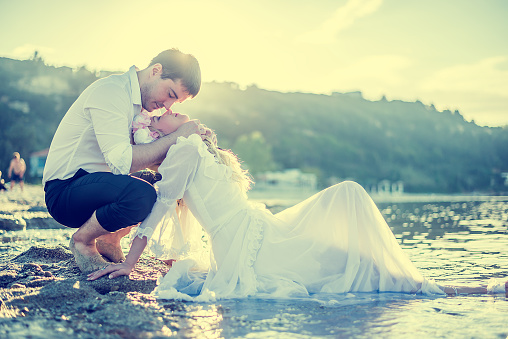 Bride and Groom enjoying in their love on the beach at sunset
