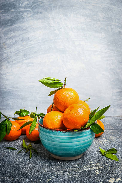 istock Fresh Tangerines with green leaves in blue bowl , side view 503886174