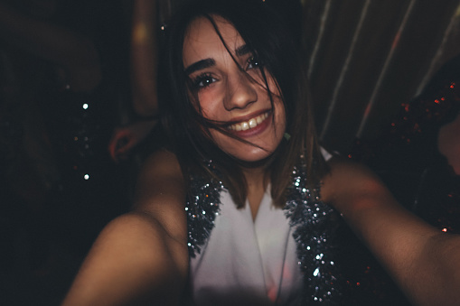Young beautiful girl is posing for a selfie during the party