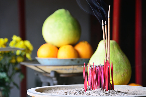 Burning prayer incense with fruints on background at a Buddhist temple