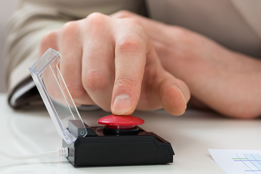 Close-up Of Businessperson Hand Pressing Red Emergency Button