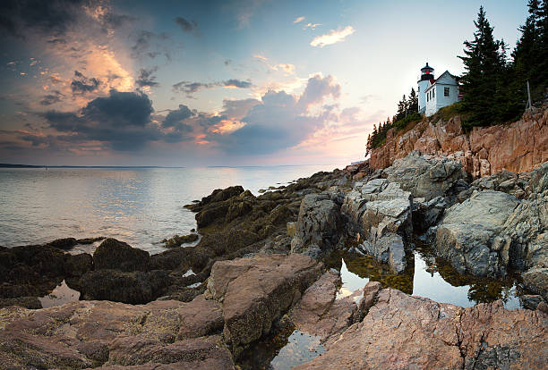 Bass Harbor Lighthouse at dusk Sunset at Bass Harbor Lighthouse, wih the light refeed inthe rock pools, Mount Desert Island, Maine, USA acadia national park maine stock pictures, royalty-free photos & images