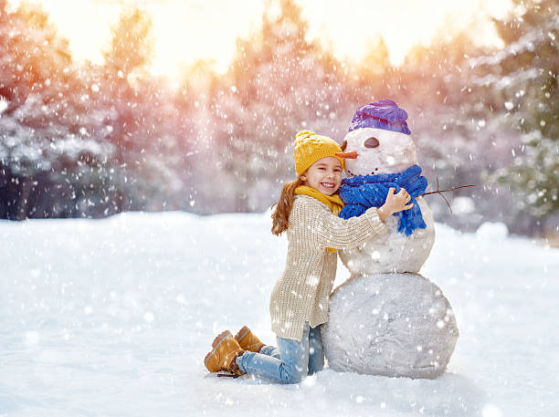 istock girl playing with a snowman 503897486