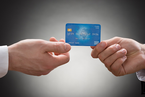 Close-up Of Two Businesspeople Hands Holding Credit Card