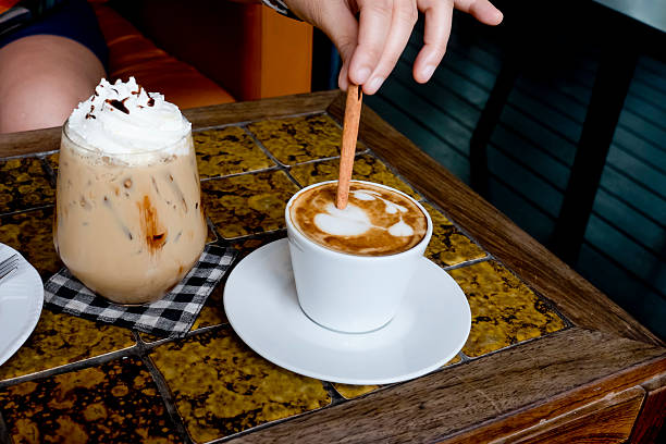 istock coffee cup Latte being stirred by Cinnamon sticks. 503898378