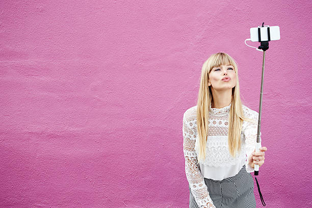 Blond beauty kissing for selfie Blond beautiful blogger kissing for selfie against pink cropped pants photos stock pictures, royalty-free photos & images