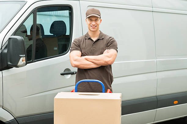 Delivery Man With Cardboard Boxes On Trolley Young Happy Delivery Man With Cardboard Boxes On Trolley In Front Of Van mover delivery person box hand truck stock pictures, royalty-free photos & images