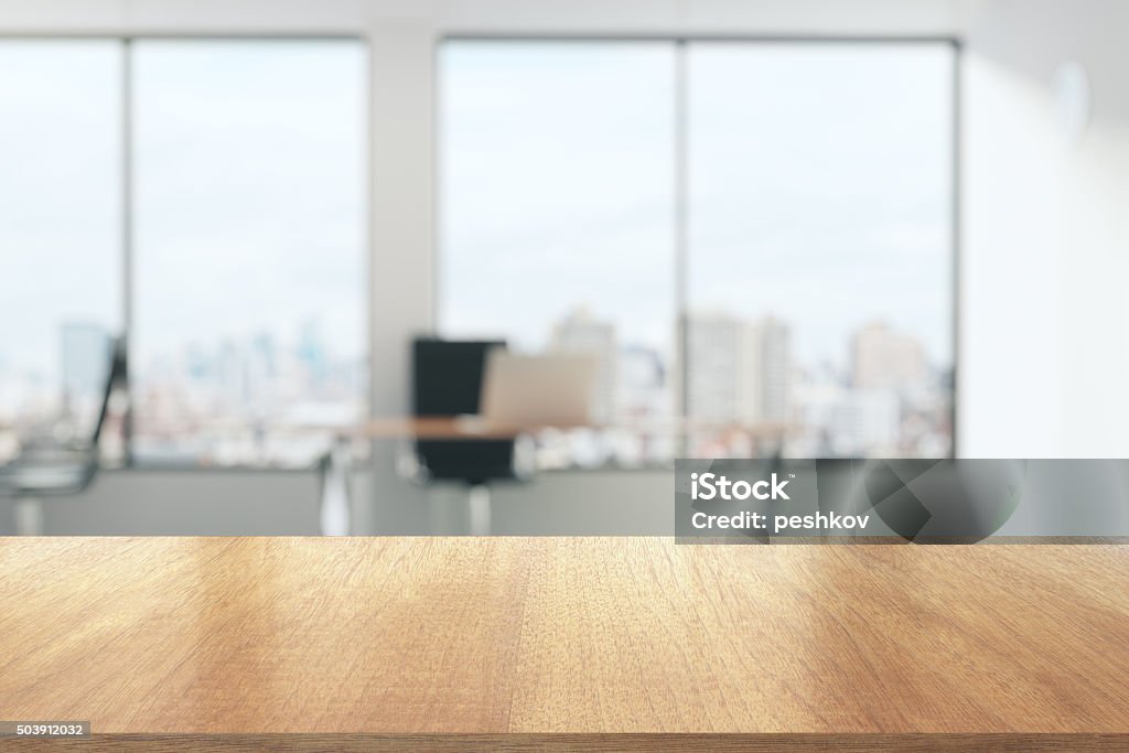 Wooden table in sunny office with big windows Office Stock Photo