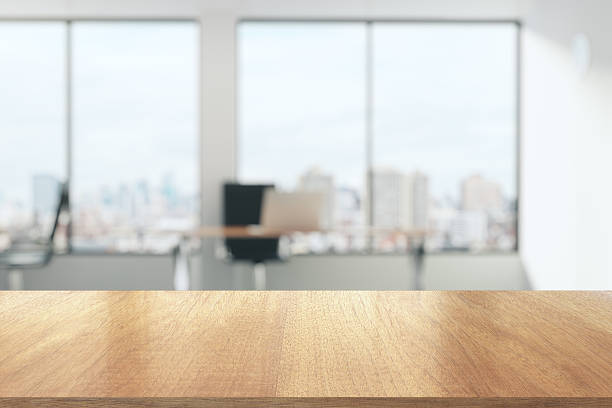 Wooden table in sunny office with big windows stock photo