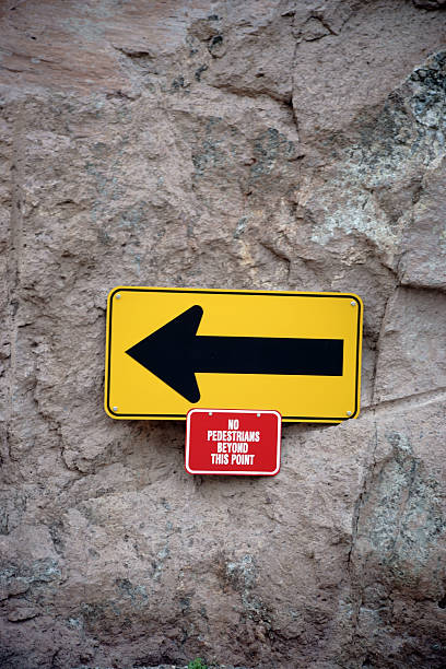 Directional arrow with warning A yellow sign with a directional arrow and a red warning label underneath. impassable limit stock pictures, royalty-free photos & images