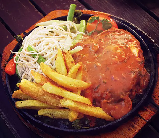 Vegetarian Sizzler in a hot round pan - instagram effect. Dinner photo with retro filter. Veggie Sizzler in a small cafe in Kathmandu, Nepal.