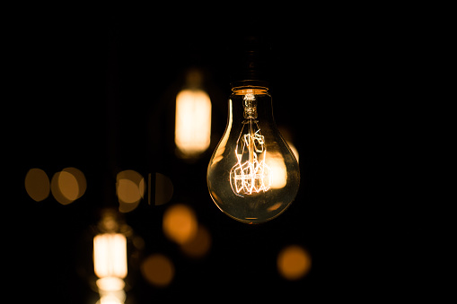 Edison light bulbs glow on black background.