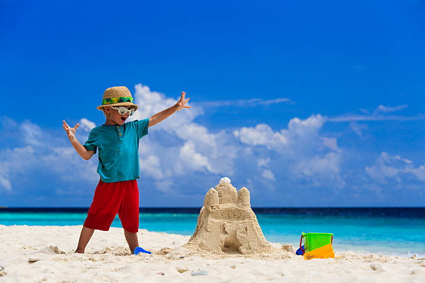 happy child with built sand castle on the beach stock photo