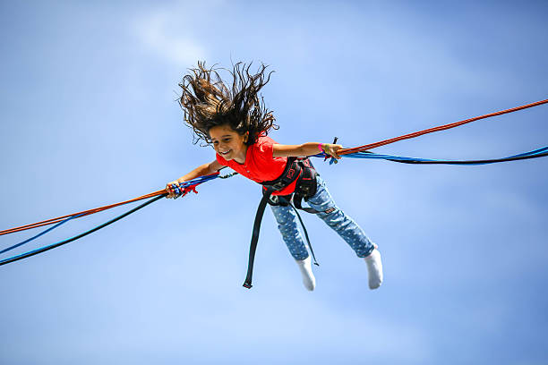 Young girl in the air Young girl in the air, holding a rubber band and bungee jumping bungee jumping stock pictures, royalty-free photos & images