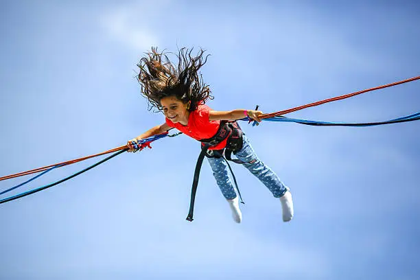 Young girl in the air, holding a rubber band and bungee jumping