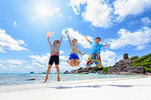 famille heureuse de sauter sur la plage en thaïlande - phuket province thailand tourist asia photos et images de collection