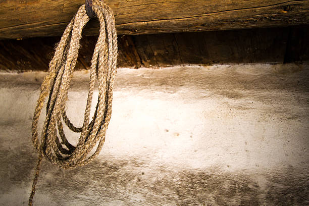 A rustic old cowboy lasso hanging from a barn beam against a dusty white wall. Shot in the Southwest.